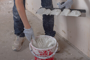Caucasian female worker putty with a spatula with putty concrete walls in the house