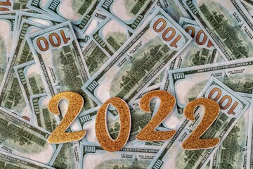 Golden numbers 2022 on a background of one hundred dollar bills. Economics and finance