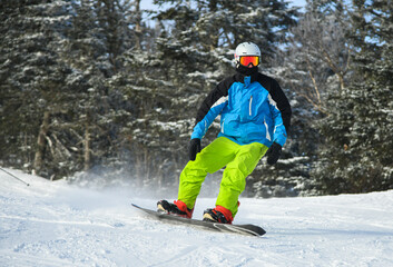 Fototapeta na wymiar Winter sports photo with male snowboarder slides at ski slope.
