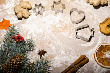 Process of making gingerbread cookies. Christmas concept. Table is covered with flour with cookie molds, spices, dried oranges and spruce branch.