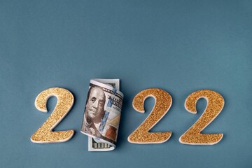 Number 2022 with a roll of one hundred dollar bills on a blue background. Copy space