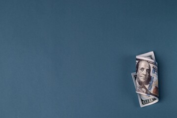 Roll of one hundred dollar bills close-up on a blue background. Copy space
