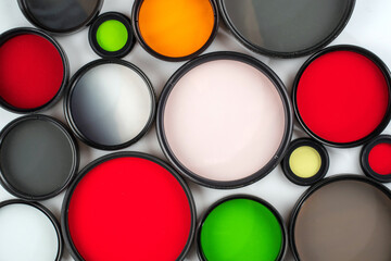 Glass round filters of different colors and sizes are isolated on a light background.
