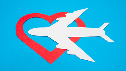 Paper plane with red heart shape on blue background.
