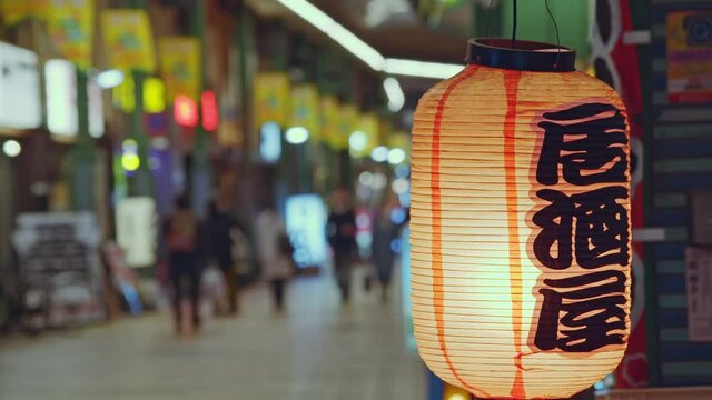 居酒屋の赤ちょうちんと商店街を歩く人々