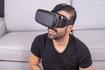 Young man in VR glasses headset at home interacting with virtual reality, smiling. close up. future technology, education video gaming