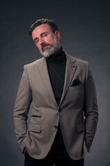 Fototapeta premium Portrait of a stylish elegant senior businessman with a beard and casual business clothes in photo studio isolated on dark background gesturing with hands