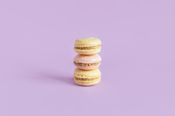 Tasty french macaroons on a violet pastel background.