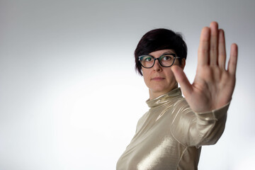 Close up portrait of woman standing with outstretched hand showing stop sign, preventing you. Female doing stop sing with palm of the hand. Warning expression with negative gesture on the face.