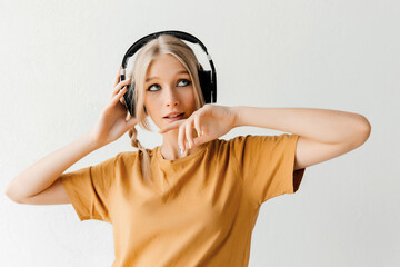 Thoughtful young woman in headphones listening to music on white background