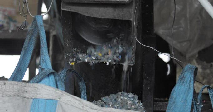Plastic shredder. Recycling. Waste shredder. Small pieces of plastic are poured into the bag. Environmental protection concept.