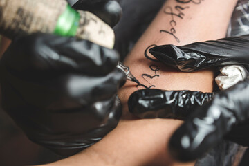 A professional tattoo artist uses a rotary tattoo machine with a round liner cartidge to outline...