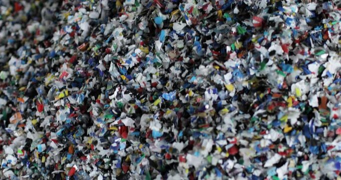 Shredded multi-colored plastic. Close-up. Waste recycling stage. The camera is moving. Environmental protection concept.