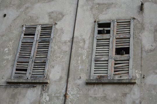 Piccioni sulle persiane rotte di una casa abbandonata.