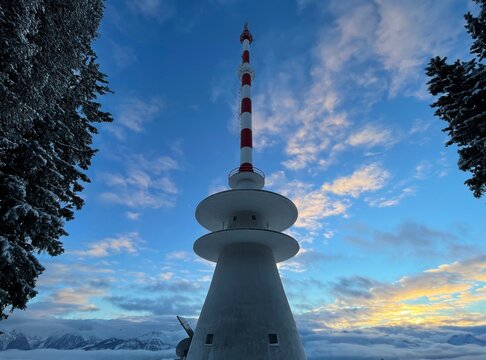 Telecommunication tower on mountain top in snow at sunset. 