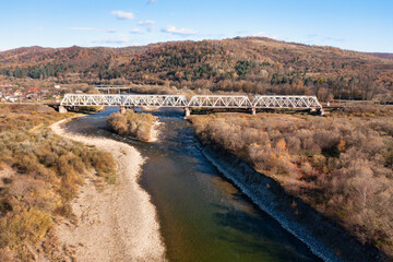 Fototapeta na wymiar Long railroad bridge over river leading to valley settlement
