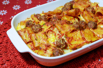 Pasta cooked in the oven, with tomato sauce, meatballs and eggs, ready to eat. Baked pasta in a porcelain dish.