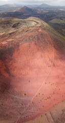 Aerial view of the path on Volcano Montana Colorada, Lanzarote, Canary Islands, Spain. Red soil covering the volcano, green bushes and volcanic ash