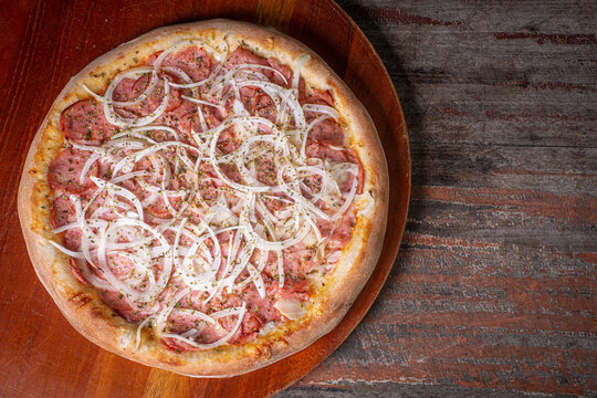 pepperoni pizza on wooden background. Brazilian pizza called pizza de calabresa. top view