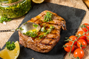 Beef steak is poured over a spoonful of homemade chimichurri green sauce, close-up.