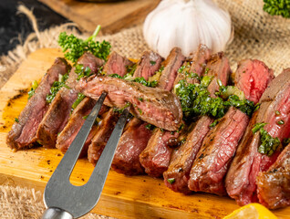 Sliced steak on a wooden board, a slice on a fork, close-up.