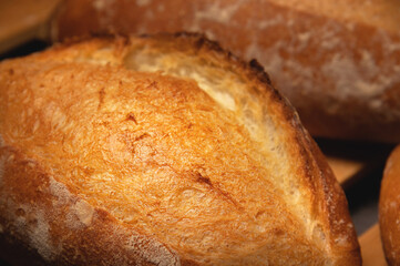 Appetizing fresh hot artisan bread. Close-up of a loaf of delicious bread on a wooden pallet