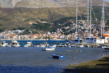 Fototapeta na wymiar Small rustic boat and flock of seagulls in the sea. Podstrana, small touristic town near Split, Croatia, is seen in the background.