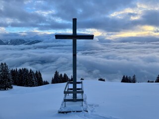 Wooden summit cross in Austrian Alps at sunset in winter. Duenser Aelpele, Vorarlberg, Austria.
