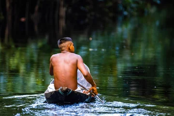 Foto op Canvas Native tribal man in amazonia rainforest in handmade boat © PhotoSpirit