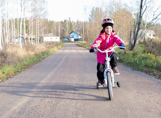 A child rides a child's bike along a rural road. Sunny day.