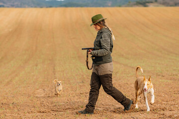Hunter woman with shotgun hunting in the field.