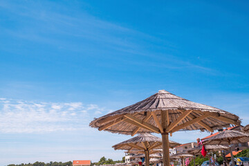 View of the beautiful blue sky and straw beach umbrellas