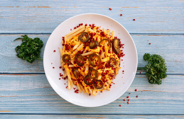 homemade spicy chili cheese fries in white plate on wooden table background top view