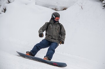 Fototapeta na wymiar a man on a snowboard rides down the side of the mountain