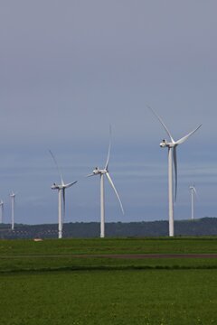 Wind turbines in an agricultural landscape in the Eastern Cape Province of South Africa with the ocean in the distance.