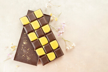 Brown and yellow fruit chocolate bars on black background. Handmade chocolate with mango, orange flavor. Healthy food concept, delicious chocolate sweets for kids, diet, sugar