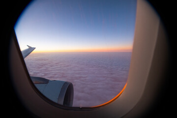 view of sea of clouds at sunset out of airplane window seat window orange sunset with pink and...