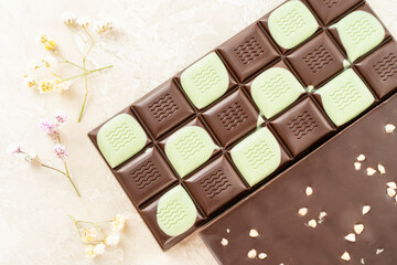 Brown and green fruit chocolate bars on black background. Handmade chocolate with mango, orange flavor. Healthy food concept, delicious chocolate sweets for kids, diet, sugar