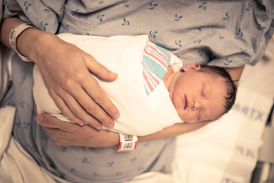 parent holding newborn baby in hospital bed 