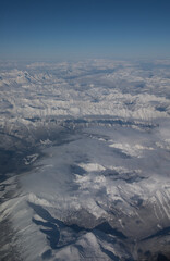 Aerial view of snow covered rocky mountains in Canada or Canadian Rockies as seen from window seat of airplane while in flight travelling on plane from Alberta, Canada to British Columbia 