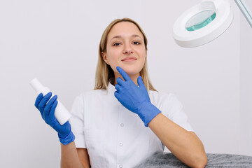 Portrait of female professional beauty doctor with a product in a hand.