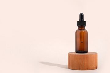 Mockup cosmetic face serum brown glass bottle with a pipette on a stylish minimalist beige white background wooden pedestal.. Female beauty concept, empty template