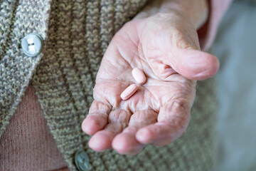 medicine pills on wrinkled palm of old person