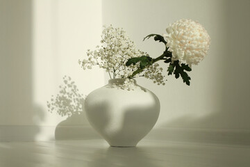 Beige chrysanthemums and gypsophila  flower in white vase on white interior. Minimalist still life. Light and shadow nature horizontal background. - obrazy, fototapety, plakaty