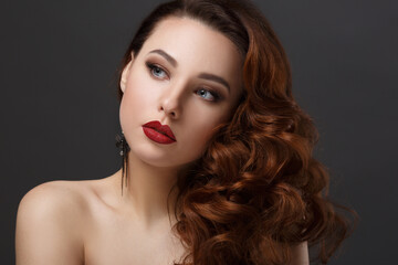Fashion beauty portrait of a beautiful girl with curly hair luxuriant on a dark background.