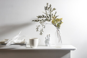 A vase with dry eucalyptus, pieces of paper, a figurine with a fox, and a cup of coffee. Scandinavian style.