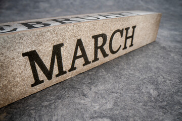 March text on grunge wooden block against handmade textured paper, calendar concept