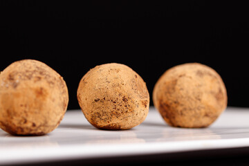 Beautiful candy truffle on a white plate on a black background