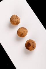 Beautiful candy truffle on a white plate on a black background