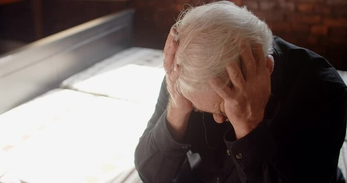 Depressed hopeless old gray haired man grieves and grabs his head with both hands, sorrow and mental breakdown, 4k 60p Prores